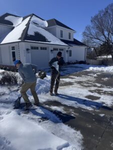 Workers performing snow removal service on a driveway by All in- Landscaping and Power-washing in Fayetteville, AR.