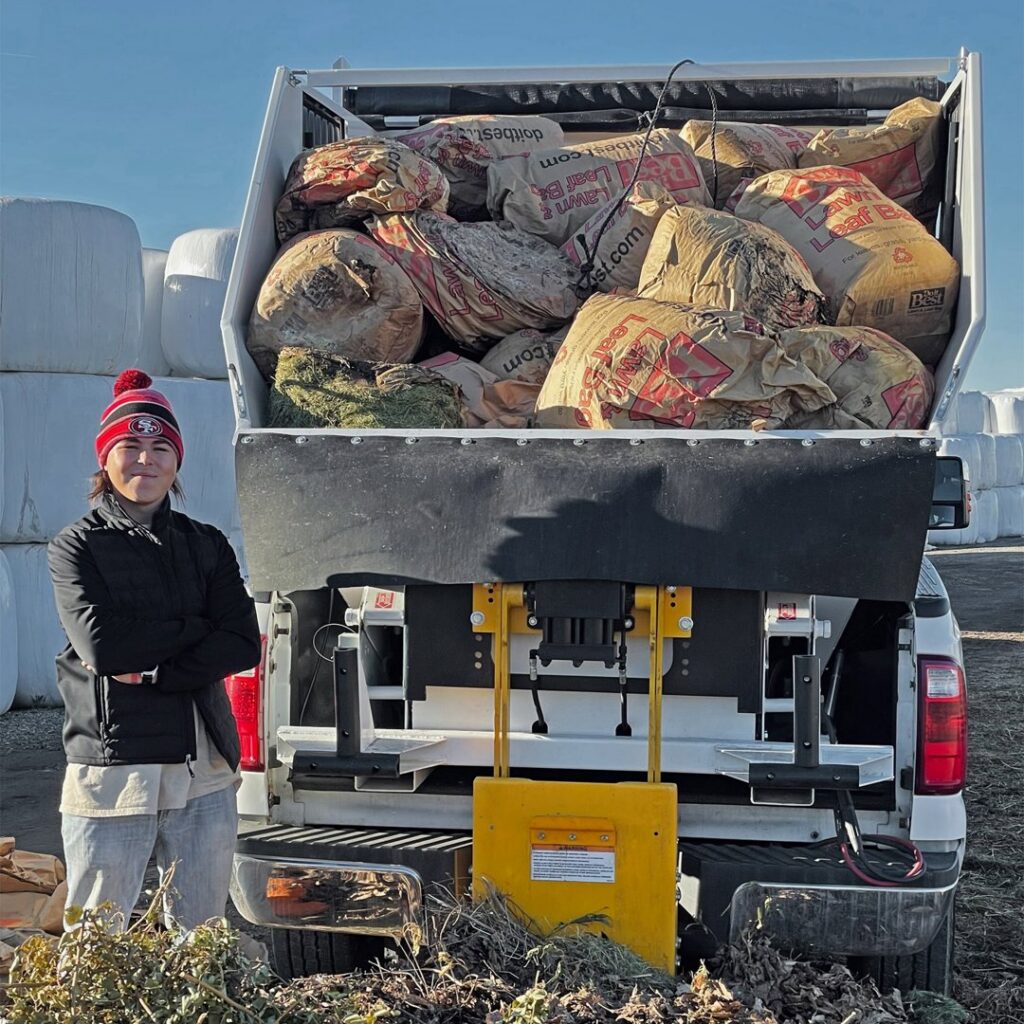 A Cali Fresh Services team member in Fort Wayne, IN, stands by a pickup truck equipped with a snow and ice removal spreader.