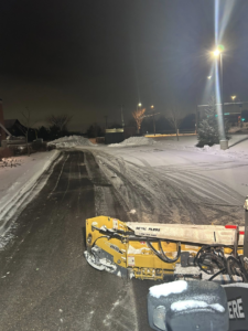 A snowplow clearing a road or driveway at night, showing effective snow removal by Cities Lawn and Snow LLC in Woodbury, MN.