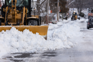 A large yellow snowplow clearing a street of heavy snow, demonstrating snow removal by City of Green Bay Public Works in Green Bay, WI.