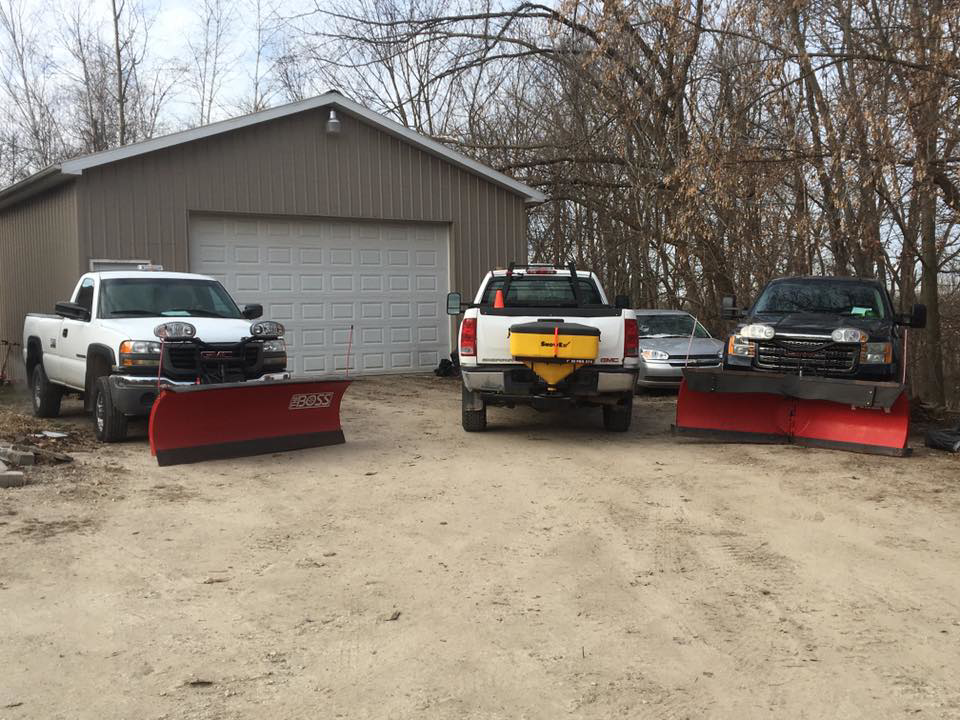 Three snowplow trucks, one with a salt spreader, ready for snow removal by Total Lawn Care & Snowplowing in Littleton, CO.