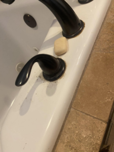 Close-up of a bathtub faucet covered in soap scum and grime, a common cleaning challenge for Cleaning with Care in Fayetteville, AR.