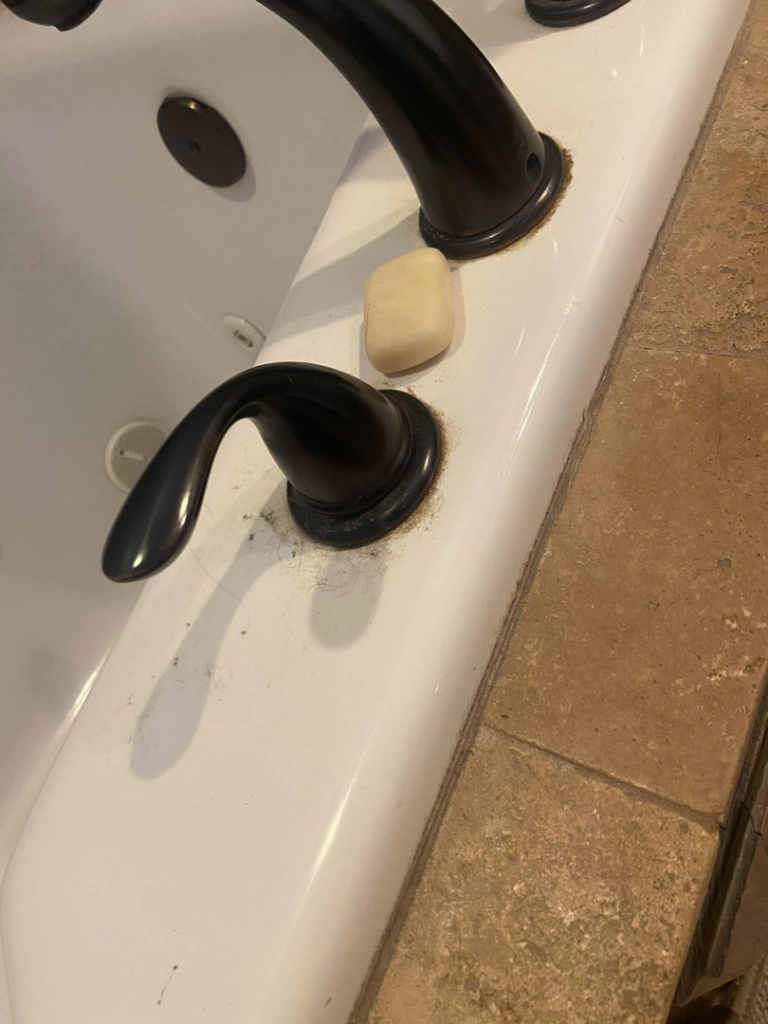 Close-up of a bathtub faucet covered in soap scum and grime, a common cleaning challenge for Cleaning with Care in Fayetteville, AR.