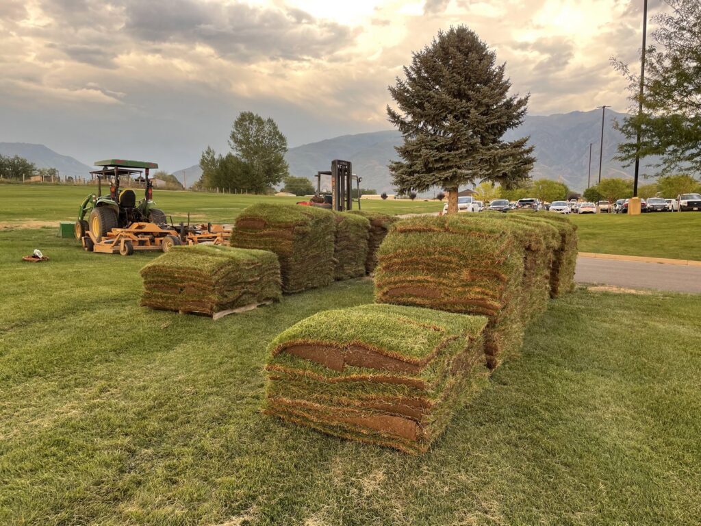 A sod harvesting operation with stacked sod, a tractor, and a forklift at Aspen Sod in Layton, UT.