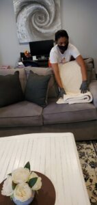 A house cleaner tidying a blanket on a sofa in a living room for TAG Team Cleaning of West Hartford, CT