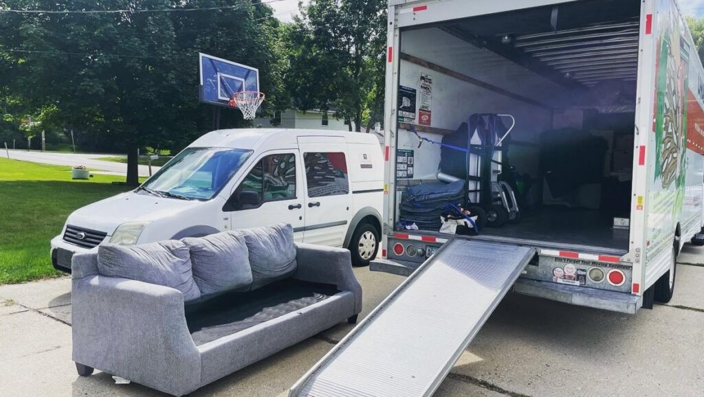 A sofa positioned next to a moving truck with a ramp, ready for loading by Shield Moving Services in Milwaukee, WI.