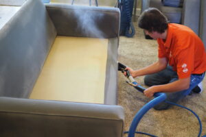 A technician performing sofa upholstery cleaning service by Idaho Gem Cleaning in Caldwell, ID.