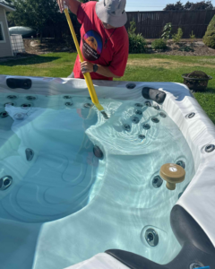 A technician cleaning a hot tub as part of spa services from Retrowave Pool & Spa in Nampa, ID.