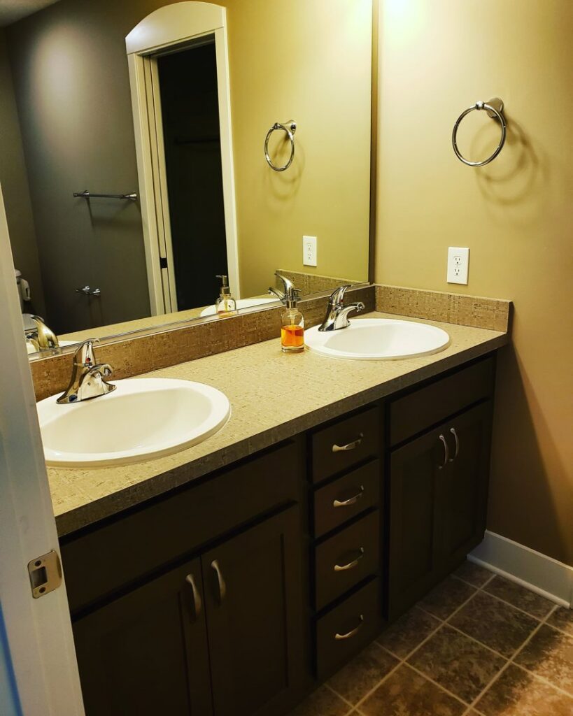 A sparkling clean bathroom vanity with double sinks and a large mirror, professionally cleaned by A To Zen in Lansing, MI.