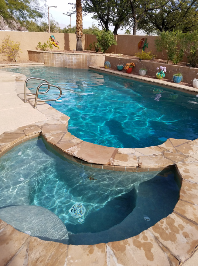A sparkling blue swimming pool and attached spa, showcasing quality cleaning by Dave Rubinson Pools in Las Vegas, NV.