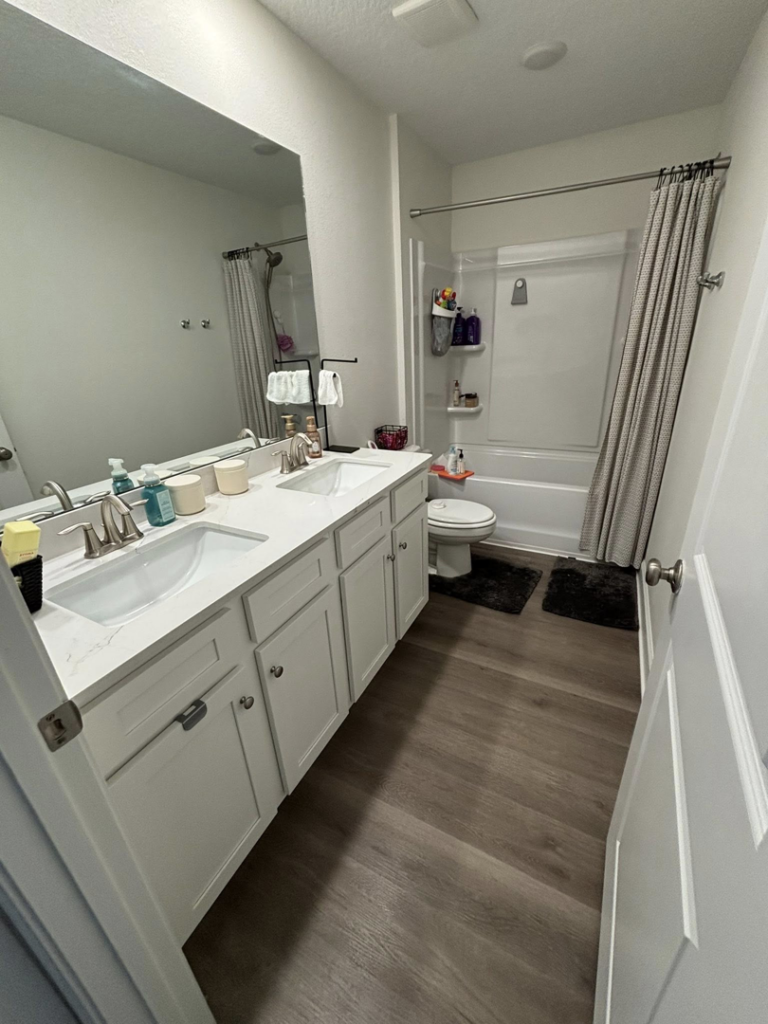 A sparkling clean bathroom featuring a double vanity and shower, cleaned by Saari's Cleaning Services LLC in Jacksonville, FL.