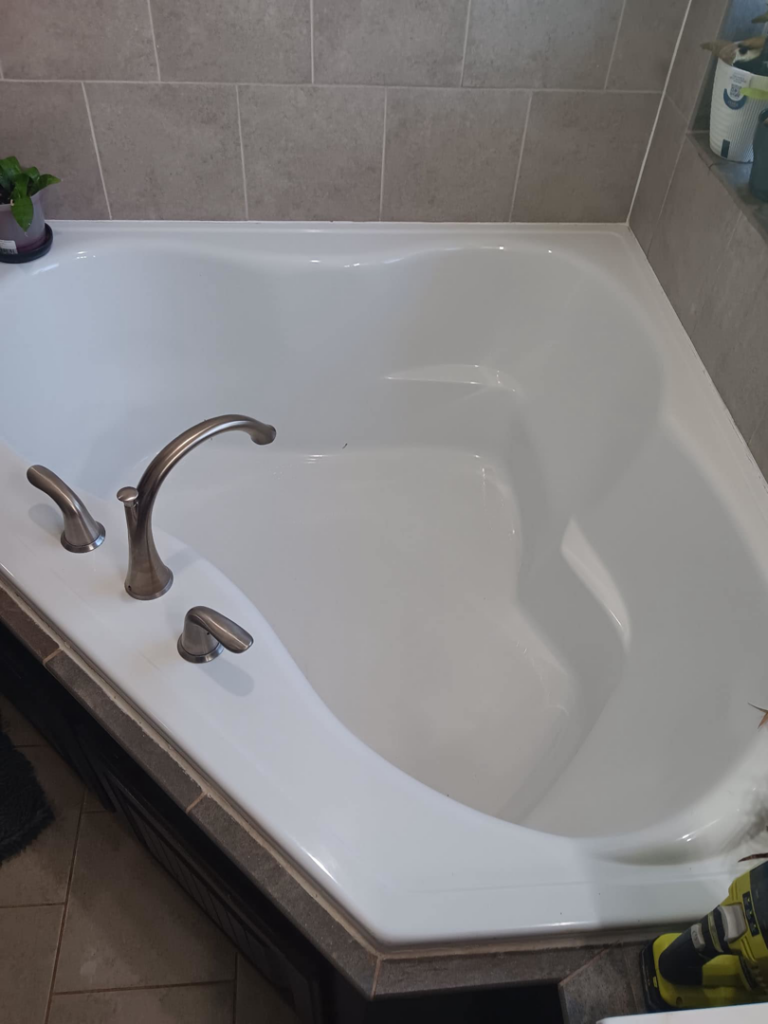 A sparkling clean bathtub with bronze fixtures, showcasing professional house cleaning by Hey Sis Cleaning LLC in Edmond, OK.