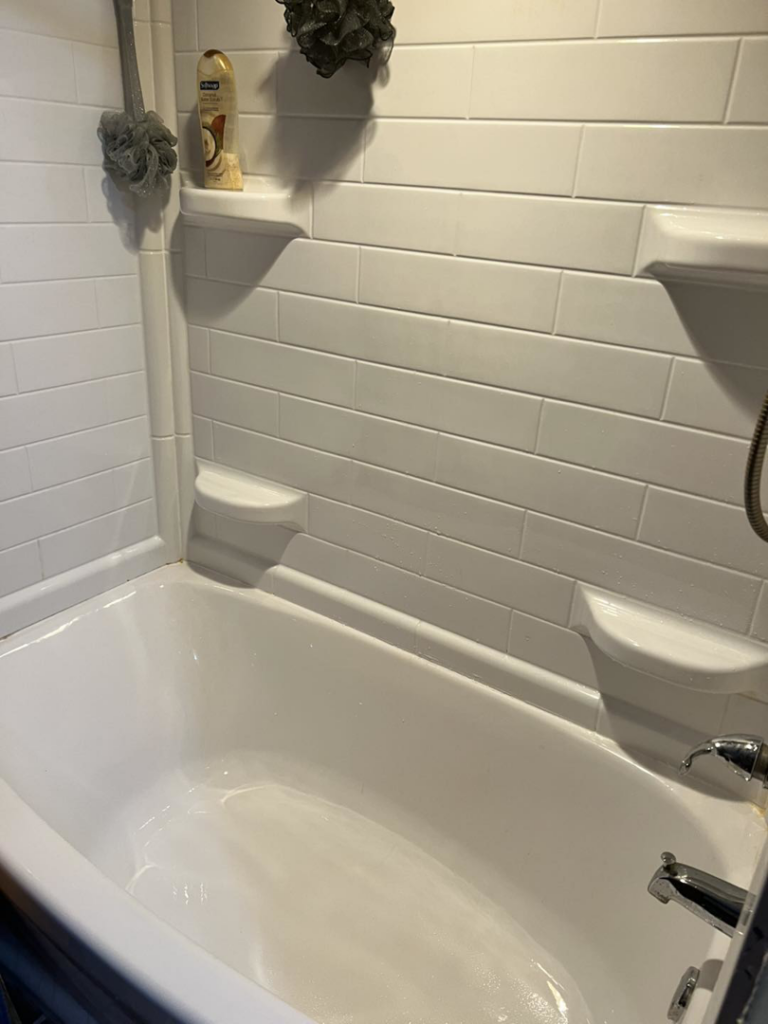 A sparkling clean white bathtub and tiled shower wall by Treadway's Cleaning Services in Spencer, IN