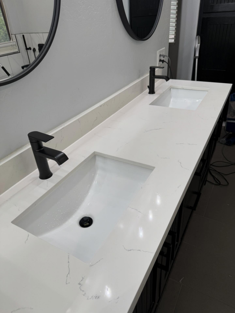 A sparkling clean double bathroom vanity with white sinks and black faucets by ClutterGone in Surprise, AZ.