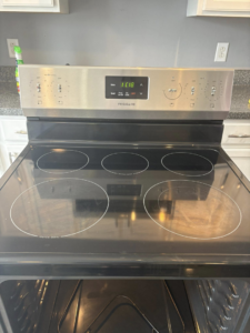 A sparkling clean black electric stovetop with stainless steel controls, demonstrating the thorough cleaning by Claudia's Cleaning Services in Clarksville, TN.