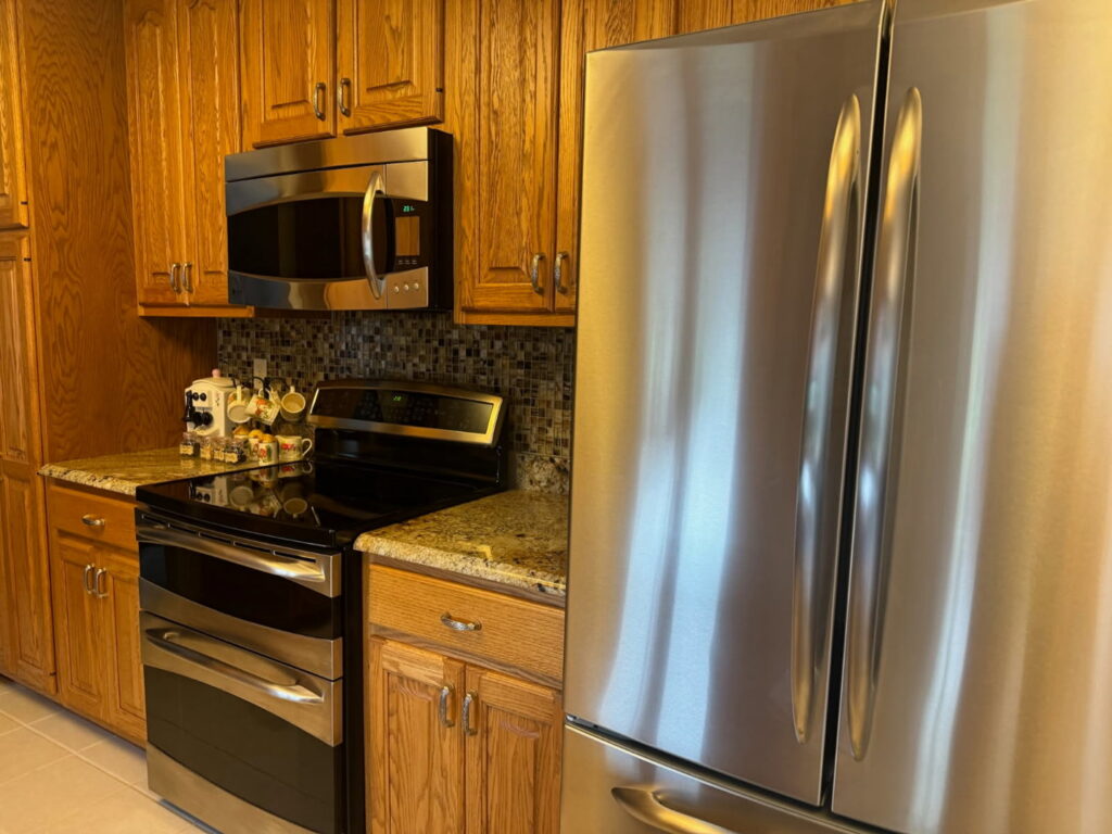 A sparkling clean kitchen with wooden cabinets and stainless steel appliances, showcasing the results of Peoria Cleaning Pros, LLC in East Peoria, IL.