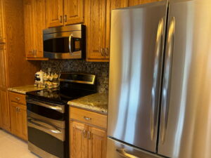 A sparkling clean kitchen with wooden cabinets and stainless steel appliances, showcasing the results of Peoria Cleaning Pros, LLC in East Peoria, IL.