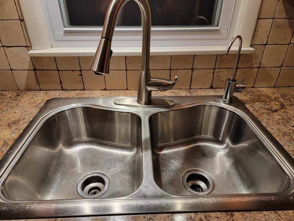 A sparkling clean stainless steel kitchen sink and faucet, showcasing the professional cleaning results from Sparkle & Shine of Iowa in Urbandale, IA.