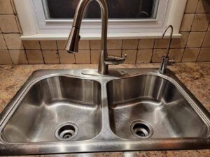 A sparkling clean stainless steel kitchen sink and faucet, showcasing the professional cleaning results from Sparkle & Shine of Iowa in Urbandale, IA.