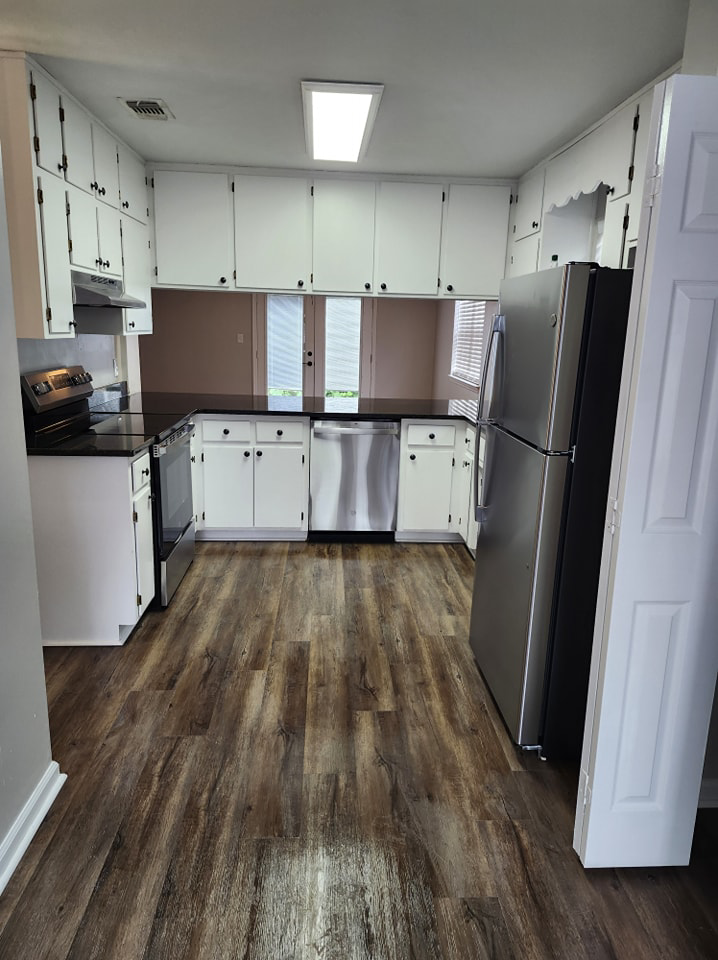 A sparkling clean kitchen with white cabinets, black countertops, and stainless steel appliances, cleaned by S&M Cleaning Services 5 LLC in Cocoa, FL.