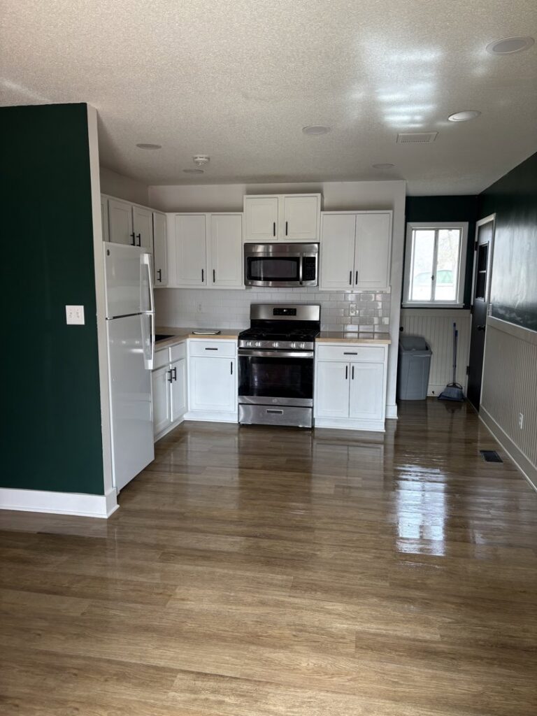 A sparkling clean residential kitchen with white cabinets and wooden floors, cleaned by Uniquely Clean Professional Services in Kansas City, MO.