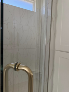 A sparkling clean glass shower door and tiled wall, demonstrating bathroom cleaning services by Global Provisions, AR in Fayetteville, AR.