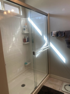 A sparkling clean shower enclosure with clear glass and white tiles by Lindi's Clean Living, LLC in Tucson, AZ.