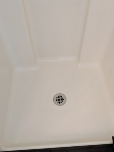 A sparkling clean shower floor with a shiny drain, demonstrating the thorough cleaning services of White Rose Cleaning in Idaho Falls, ID.