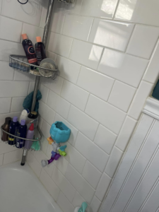Sparkling clean white subway tiles and a shower caddy in a bathroom cleaned by Shine Bright Cleaning Co. in Overland Park, KS.