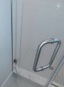 A sparkling clean shower with clear glass and white tiles, expertly cleaned by White Lotus Cleaning Services LLC in Nashua, NH.