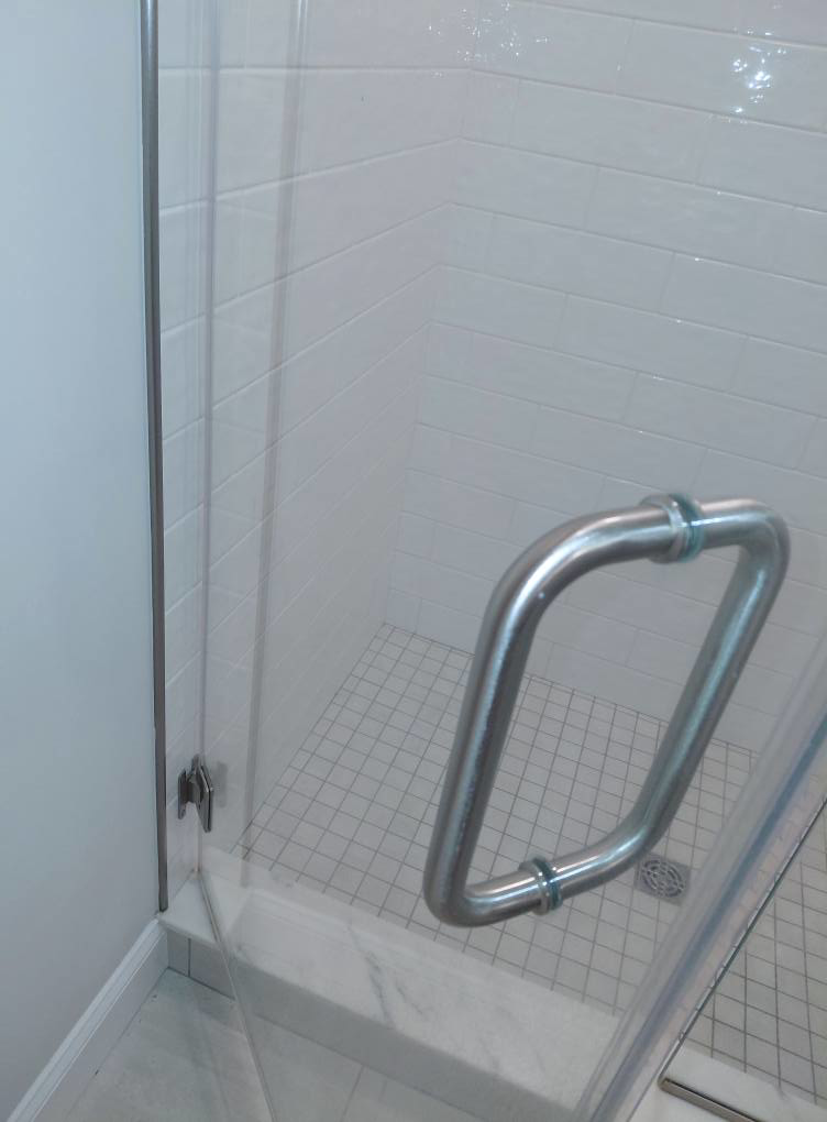 A sparkling clean shower with clear glass and white tiles, expertly cleaned by White Lotus Cleaning Services LLC in Nashua, NH.