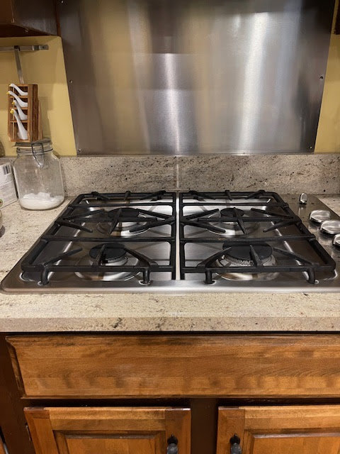 A sparkling clean stainless steel stovetop, showcasing the detailed kitchen cleaning by Straight Up Cleaning in South Portland, ME.