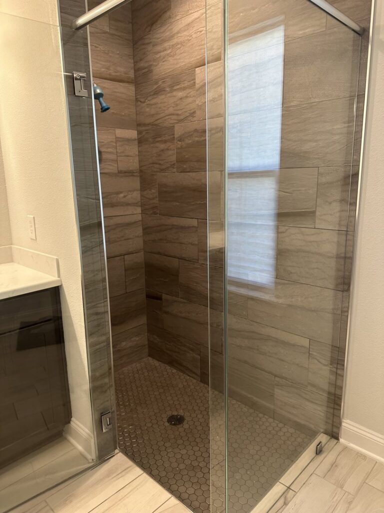 A sparkling clean glass shower with elegant tiled walls and floor, expertly cleaned by CLEAN That SHEET LLC in Jacksonville, FL.
