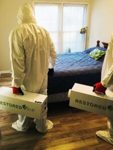 Restored Air specialists in PPE carrying air scrubbers into a bedroom for remediation services in Summerville, SC.