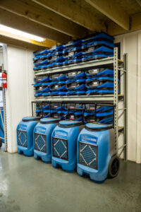A storage rack filled with specialized water damage drying equipment and dehumidifiers at Claim Masters in New Hartford, NY.