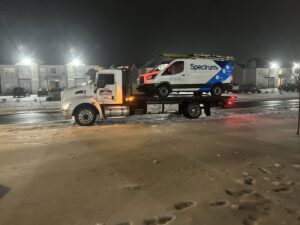 A Spectrum service van loaded onto a flatbed tow truck from Wilkerson's Towing & Automotive LLC at night in Bowling Green, KY.