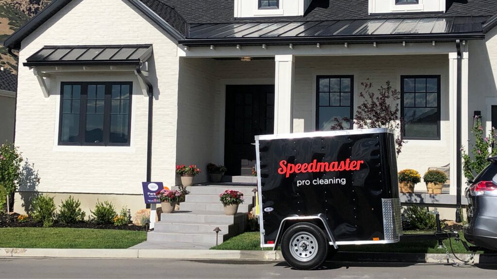 A Speedmaster Pro Cleaning trailer parked in front of a modern house, indicating on-site house cleaning services in Salt Lake City, UT.