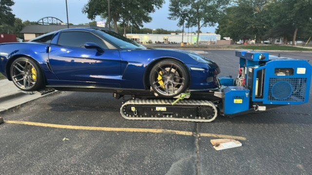 A blue sports car being towed with specialized low-clearance equipment by Jim & Ron's Service Inc. in Sioux Falls, SD.