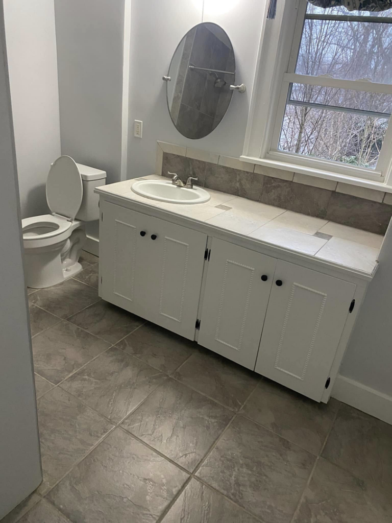 A spotless bathroom with a clean toilet, vanity, and tiled floor, cleaned by Kings and Queens of the Most High Cleaning Services in Akron, OH.
