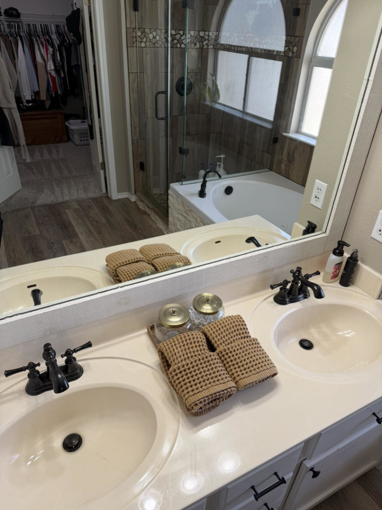 A spotless bathroom vanity with double sinks and neatly folded towels, cleaned by Lupita's cleaning services in San Antonio, TX.