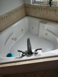 A spotless white corner bathtub with shiny chrome fixtures, showcasing professional cleaning by S&M Cleaning Services 5 LLC in Cocoa, FL.