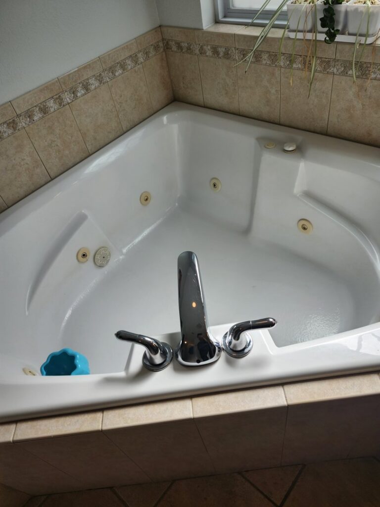 A spotless white corner bathtub with shiny chrome fixtures, showcasing professional cleaning by S&M Cleaning Services 5 LLC in Cocoa, FL.