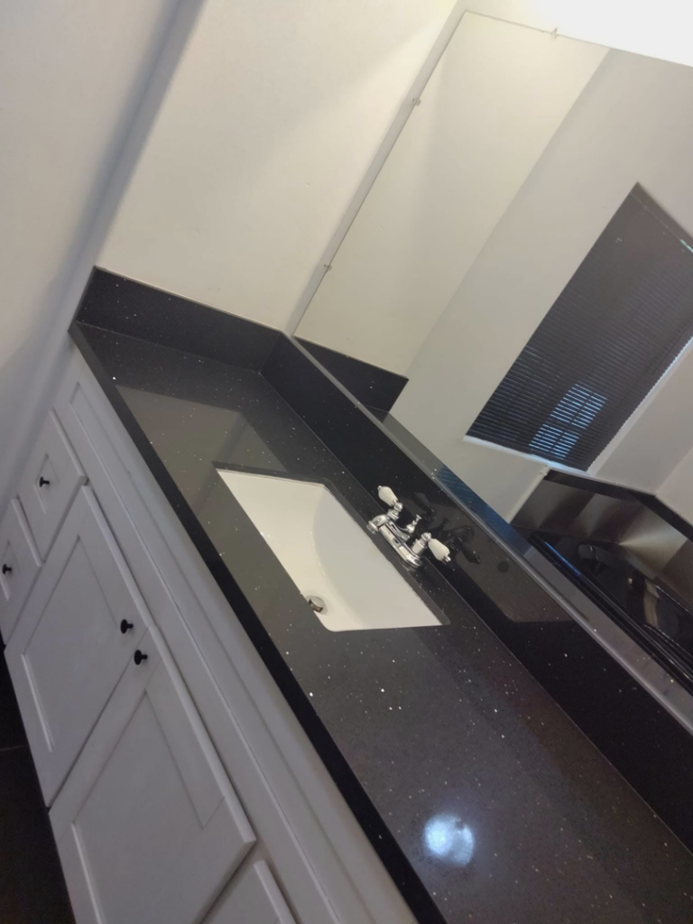 A spotless glass shower enclosure with a unique pebble floor, demonstrating the meticulous cleaning services by Bright City Residential Cleaning in North Las Vegas, NV.