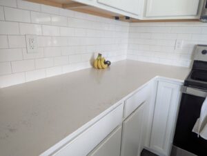 A spotless kitchen counter with white subway tile backsplash and cabinets, showcasing cleaning by Columbia Cleaners in Columbia, MO.