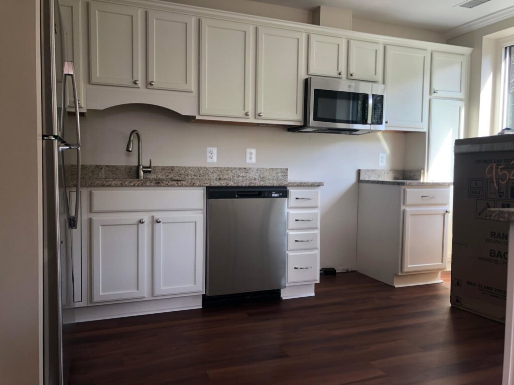 A spotless kitchen featuring white cabinets, a stainless steel dishwasher, and granite countertops, cleaned by Rivas Molina's Cleaning LLC in Dundalk, MD.
