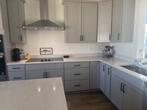 A spotless modern kitchen with grey cabinets and white countertops, expertly cleaned by Nichole's Cleaning Service in Fort Wayne, IN