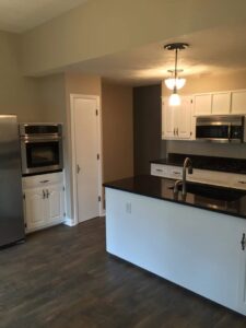 A spotless kitchen featuring white cabinets and black countertops, cleaned by Price Cleaning Services Omaha in Council Bluffs, IA.