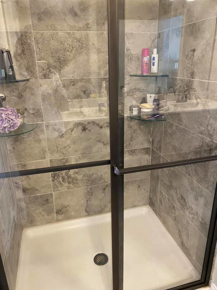 A spotless modern shower with grey tiles and clear glass, professionally cleaned by Tip Top Cleaning in Champaign, IL.