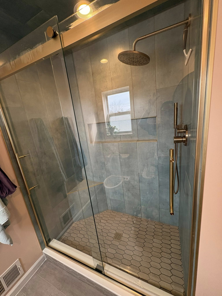 A spotless modern shower with glass doors and tiled walls, professionally cleaned by HDew Cleaning Co. in Madison Heights, MI.
