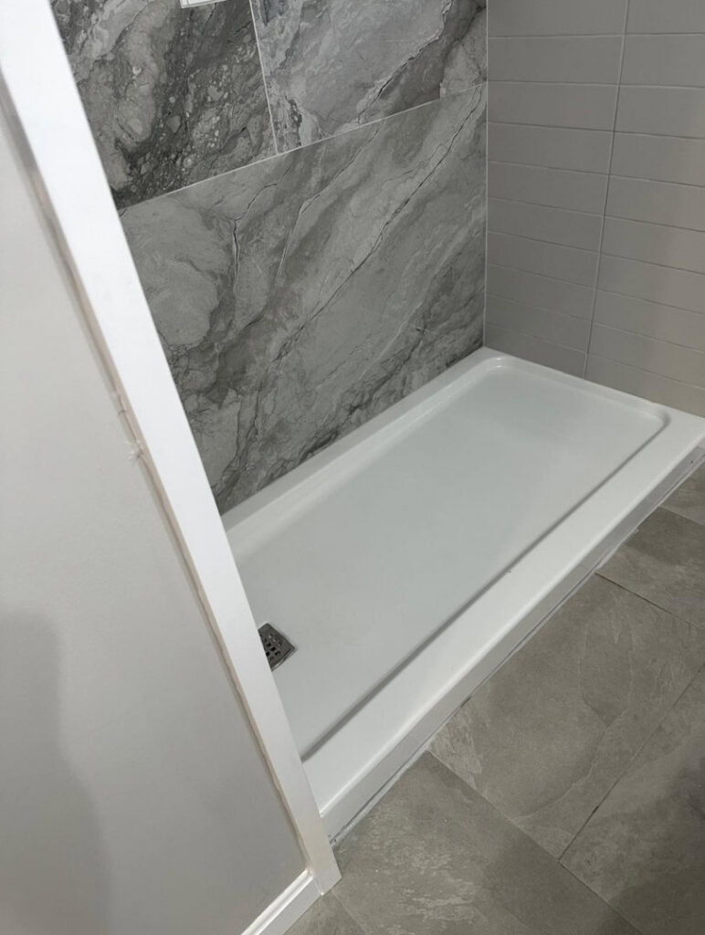 A spotless white shower base and clean tiled walls, demonstrating the detailed cleaning services of Mary's Sparkling Cleaning in Fall River, MA.